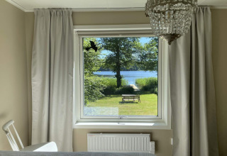 Vista desde la ventana del dormitorio hacia el lago en Lakeside Cabin Retreat en Sollentuna, Suecia, en un día soleado.