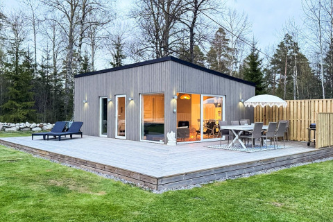 Modern 4-sterren vakantiehuis in Hestra met groot houten terras, tuinmeubilair en groene gazon.