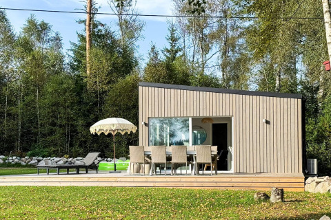 Lodge moderno con zona pranzo esterna, ombrellone e lettini presso casa vacanze 4 stelle a Hestra, Svezia.