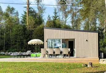Moderne lodge met buitenterras, parasol en ligzetels bij 4-sterren vakantiehuis in Hestra, Zweden.