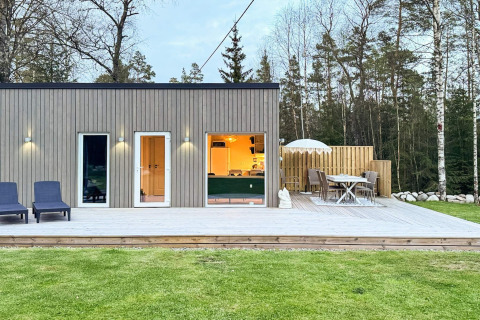 Moderne lodge met houten terras en zitgedeelte bij ‘4 star holiday home in Hestra’ in Zweden, omgeven door natuur.