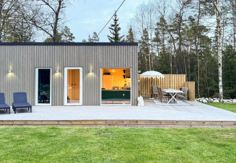 Cabaña moderna con terraza de madera, tumbonas y comedor en "4 star holiday home in Hestra", Suecia.