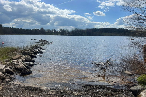 Aussicht auf einen See mit Steinweg bei 4 star holiday home in Hestra, Schweden, unter wolkigem Himmel.
