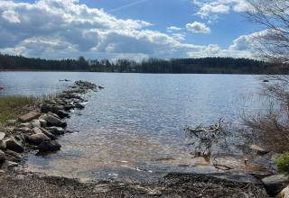 Aussicht auf einen See mit Steinweg bei 4 star holiday home in Hestra, Schweden, unter wolkigem Himmel.