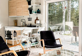 Moderne Zweedse vakantiewoning in Hestra met compacte keuken, salon en zicht op terras en bos.