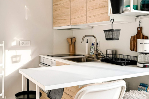 Area cucina moderna in casa vacanze a Hestra, Svezia, con pensili in legno, tavolo bianco e macchina da caffè.