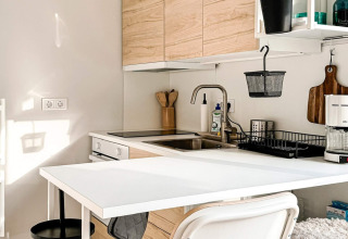 Moderne Küchenzeile im Ferienhaus in Hestra, Schweden, mit Holzfronten, weißem Tisch und Kaffeemaschine.