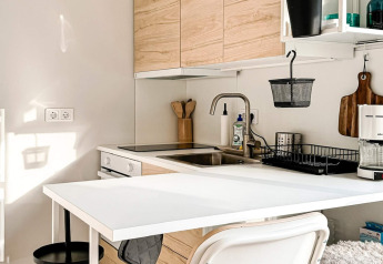 Moderne keukenruimte in een vakantiewoning in Hestra, Zweden, met houten kasten en een witte tafel.