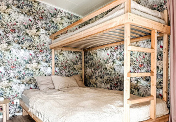 Houten stapelbed met dubbel bed onderaan en enkel bed bovenaan in een gezellige lodge in Hestra, Zweden.