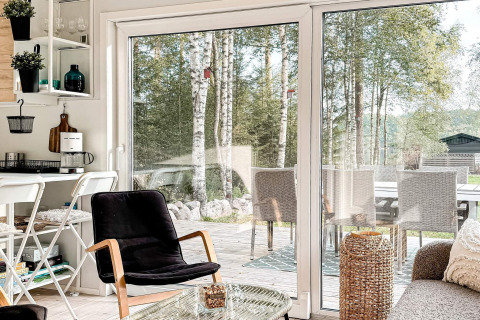 Lichte, moderne woonkamer in een vakantiehuis in Hestra, Zweden, met glazen deuren naar het terras.
