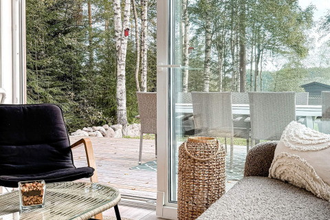 Luminoso soggiorno accogliente con mobili moderni, vista sul patio e foresta in una casa vacanza a Hestra.