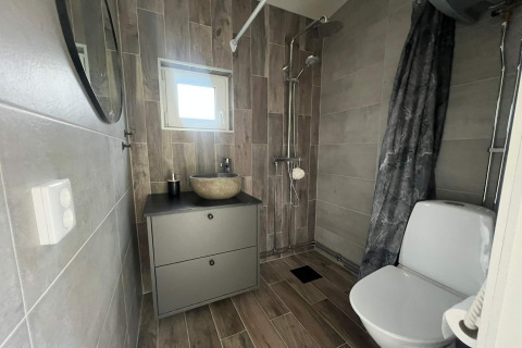Moderne badkamer met douche, toilet, wastafel en spiegel in een vakantiehuis in Hestra, Zweden.