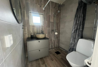 Modernes Badezimmer mit Dusche, WC, Waschbecken und Spiegel in einer Lodge in Hestra, Schweden.