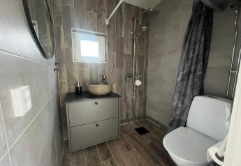 Moderne badeværelse med toilet, bruser, håndvask og spejl i en lodge i Hestra, Sverige.
