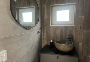 Moderne badkamer met stenen waskom, rond spiegel en klein raam in vakantiewoning in Hestra, Zweden.