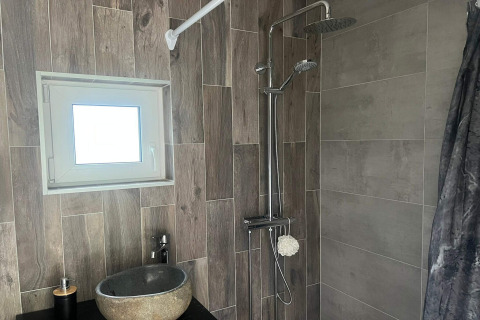 Moderne badkamer in een 4-sterren vakantiehuis in Hestra, Zweden, met douche, stenen wastafel en raam.