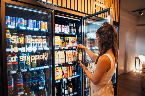 Frau nimmt eine Flasche Wein aus einem Getränkekühlschrank im Eurocamping Vessem BV, Nordbrabant, Niederlande.