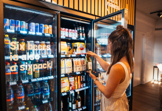 Frau nimmt eine Flasche Wein aus einem Getränkekühlschrank im Eurocamping Vessem BV, Nordbrabant, Niederlande.