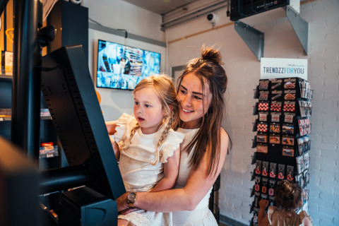Mother and daughter using a self-checkout terminal at Eurocamping Vessem BV holiday park in Netherlands.
