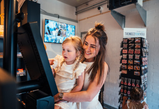 Mother and daughter using a self-checkout terminal at Eurocamping Vessem BV holiday park in Netherlands.