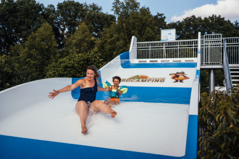 Frau und Kind rutschen eine Wasserrutsche im Eurocamping Vessem BV, Nordbrabant, Niederlande, hinunter.
