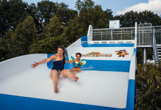 Vrouw en kind op een waterglijbaan bij Eurocamping Vessem BV, vakantiepark in Noord-Brabant, Nederland.