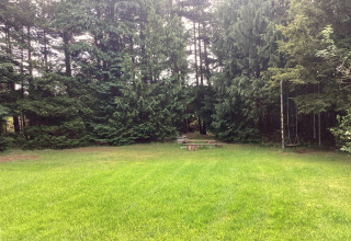 Grønt græsareal med bænk og gynge i udkanten af en skov ved 6-personers feriehus i Idestrup, Danmark.