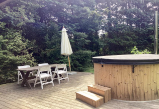 Udendørs terrasse ved 6 personers feriehus i Idestrup, Danmark med spisebord og rund spa med låg.