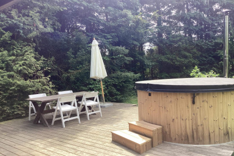 Terrasse eines 6-Personen-Ferienhauses in Idestrup, Dänemark, mit Esstisch und überdachtem Whirlpool.