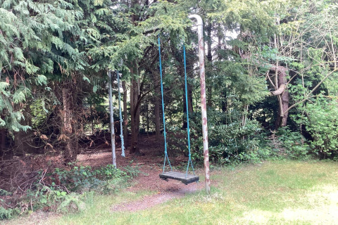 An old swing with blue ropes sits in a green backyard at '6 person holiday home in Idestrup', Denmark.
