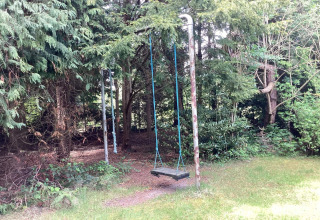 An old swing with blue ropes sits in a green backyard at '6 person holiday home in Idestrup', Denmark.