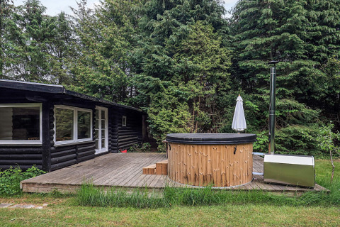 Outdoor wooden deck with hot tub in front of cabin at 6 person holiday home in Idestrup, Denmark.