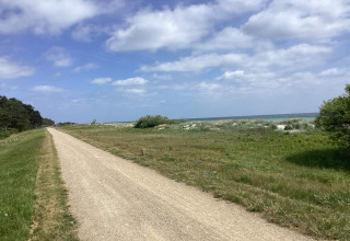 Ein Kiesweg neben Feldern mit Blick aufs Meer in der Nähe eines Ferienhauses in Idestrup, Dänemark.