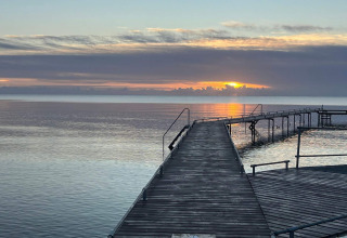 Alba sul mare vista dal pontile della casa vacanze per 6 persone a Idestrup, Danimarca.