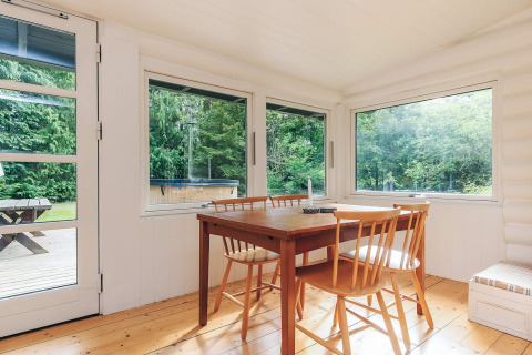 Heller Essbereich in einem Ferienhaus in Idestrup, Dänemark, mit Holztisch und Blick ins Grüne.