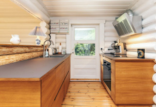 Moderne keuken met houten kasten, ingebouwde toestellen en veel licht in een lodge in Idestrup, Denemarken.
