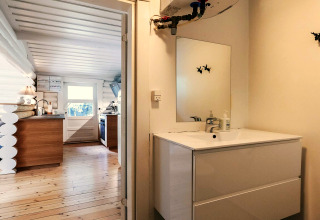 Billede af et moderne badeværelse og køkken i en feriebolig i Idestrup, Danmark, med træinteriør.