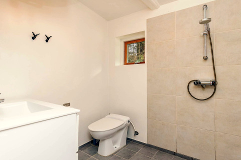 Moderne badeværelse i feriebolig i Idestrup, Danmark, med bruseniche, toilet og håndvask.