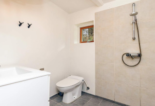 Moderne badkamer in een vakantiehuis in Idestrup, Denemarken, met douche, toilet en wasmeubel.
