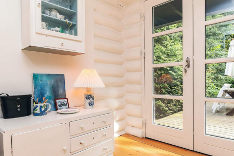 Bright corner in a holiday lodge in Idestrup, Denmark, featuring white decor, glass doors, and garden view.