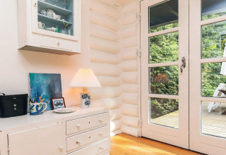 Angolo luminoso di una casa vacanze a Idestrup, Danimarca, con mobili bianchi, porte a vetri e vista giardino.