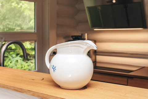 Cruche en céramique blanche avec motif bleu posée sur un plan de travail en bois dans une maison de vacances à Idestrup.