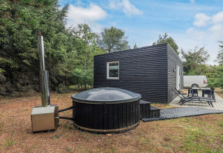 Cabaña moderna negra con jacuzzi exterior y terraza en 5-person-holiday-park-home-in-Pandrup, Dinamarca.