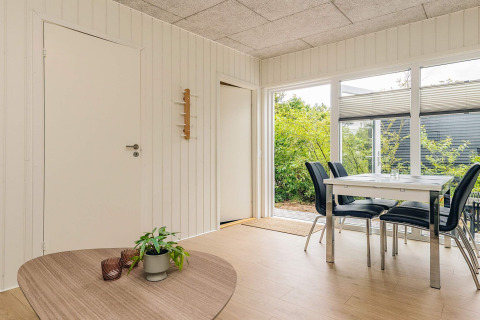 Comedor luminoso en cabaña vacacional en Pandrup, Dinamarca, con mesa moderna y vistas al jardín.