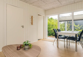 Comedor luminoso en cabaña vacacional en Pandrup, Dinamarca, con mesa moderna y vistas al jardín.