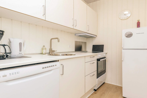 Cocina moderna blanca en una casa de vacaciones con lavavajillas, hervidor, cocina y refrigerador en Pandrup.