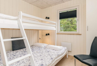 Dormitorio luminoso con litera, cama individual, silla y ventana en una cabaña en Pandrup, Dinamarca.