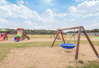 Parque infantil con columpios, toboganes y estructuras de juego sobre arena en Pandrup, Dinamarca.