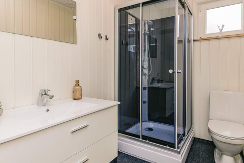 Baño moderno con lavabo blanco, cabina de ducha y WC en casa de vacaciones para 5 personas en Pandrup, Dinamarca.