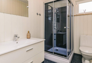 Baño moderno con lavabo blanco, cabina de ducha y WC en casa de vacaciones para 5 personas en Pandrup, Dinamarca.